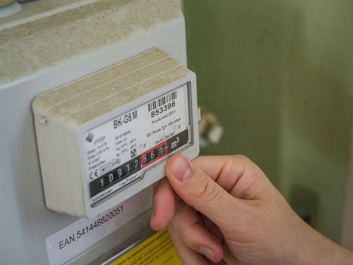 Mão apontando para um medidor de energia elétrica